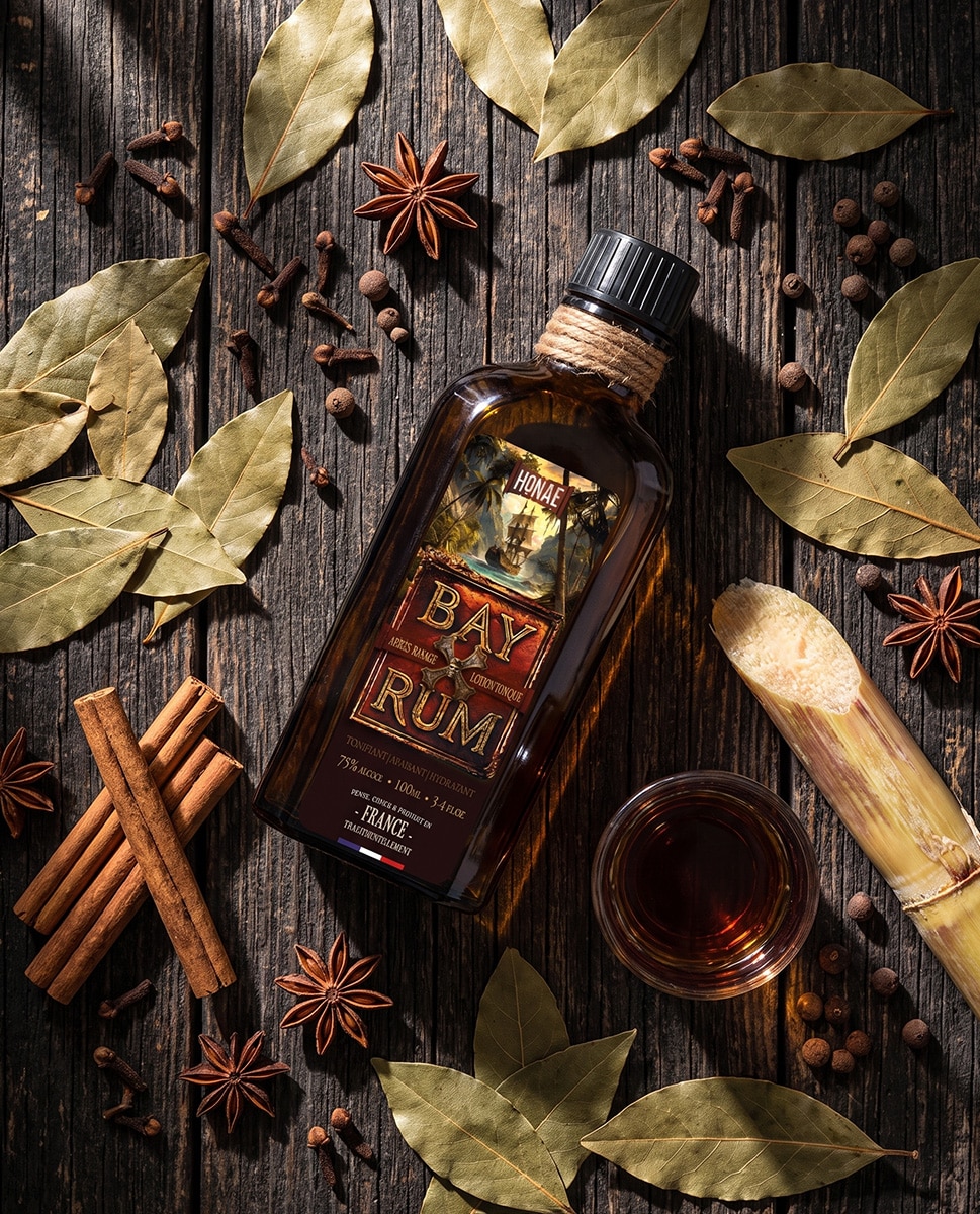 Bay Rum HONAE – laurier, épices et canne à sucre Après-rasage Bay Rum HONAE entouré de feuilles de laurier, bâtons de cannelle, clous de girofle, badiane et canne à sucre